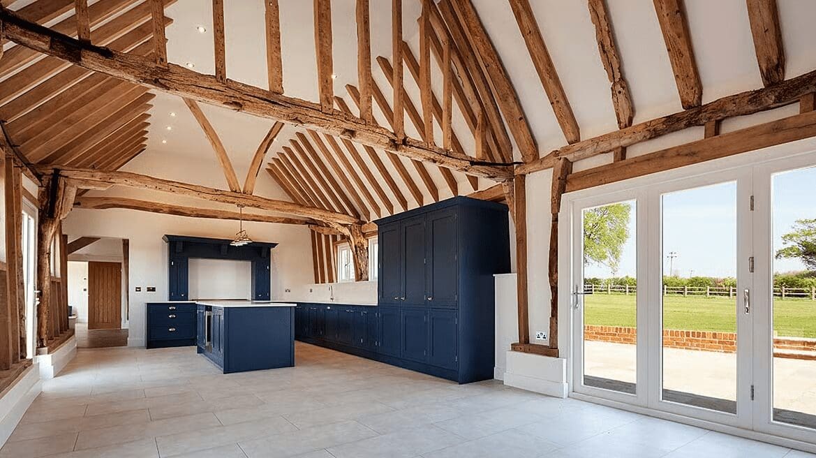 Open kitchen with exposed beams and navy cabinets